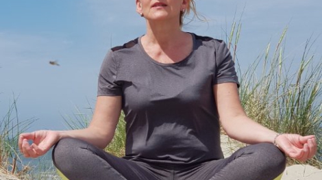 Helga mediteert op een duin op Vlieland tijdens workation